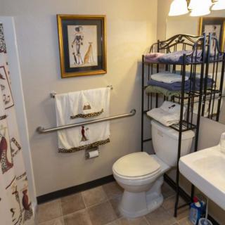 A neatly organized bathroom featuring a toilet, sink, shelving with towels, and decorative elements.