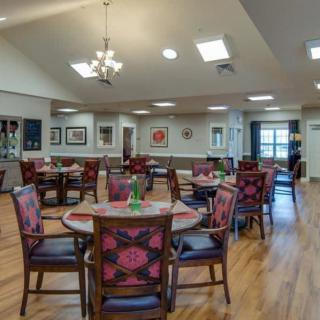 A spacious dining room with multiple tables and chairs, decorated with art and elegant lighting.