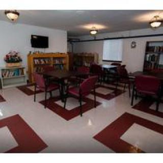 A cozy library reading room with tables, chairs, and bookshelves.