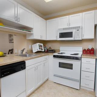 A modern kitchen with white cabinets and standard appliances.