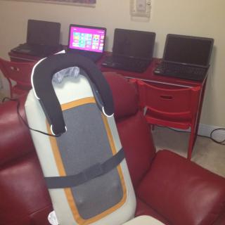 An office space with four laptops and a massage chair.