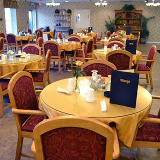 A neatly arranged dining area with round tables and red-cushioned chairs.