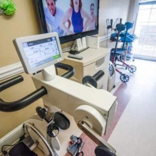 A rehabilitation room equipped with stationary exercise bikes and a monitor for virtual fitness sessions.