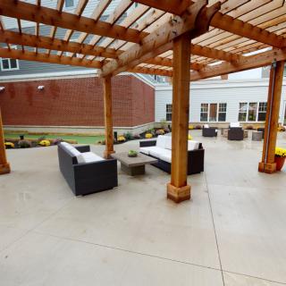 An outdoor patio featuring a wooden pergola with comfortable seating.