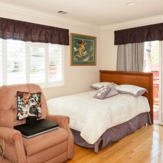 A cozy bedroom with a single bed, an armchair, and window curtains.