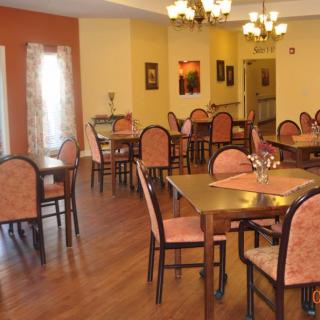 A well-lit dining area with neatly arranged tables and chairs, featuring warm decor.