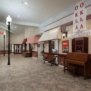 A vintage-style museum exhibit featuring storefronts, a piano, and street lamps.
