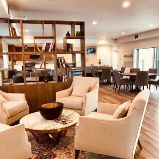 A modern and cozy living room featuring a comfortable seating area with armchairs, a round coffee table, and stylish shelving.