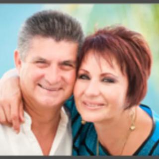 A smiling couple embraces in an outdoor setting.