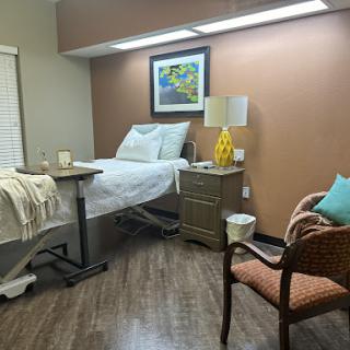 A cozy and well-lit patient room featuring a bed, decorative elements, and comfortable seating.
