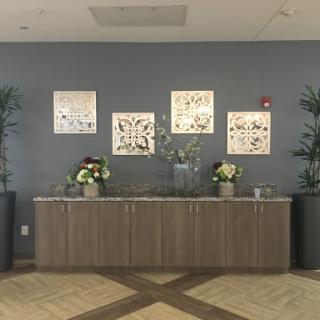 A modern lobby featuring a wooden reception counter, decorative wall art, and lush indoor plants.