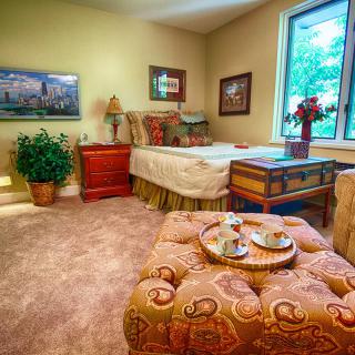 A cozy bedroom with elegant decor, featuring a bed, wooden furniture, and warm lighting.