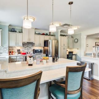 A modern kitchen with white cabinets and a central island, featuring stainless steel appliances and elegant pendant lighting.