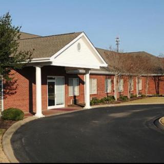 A single-story brick office building with a white entrance and circular driveway.