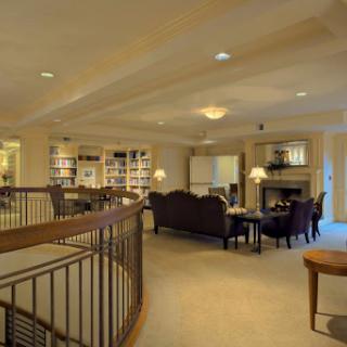 A spacious and inviting living room with a library area, featuring comfortable furniture and a warm fireplace.
