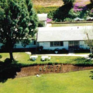 Aerial view of a suburban house with a garden and surrounding trees.
