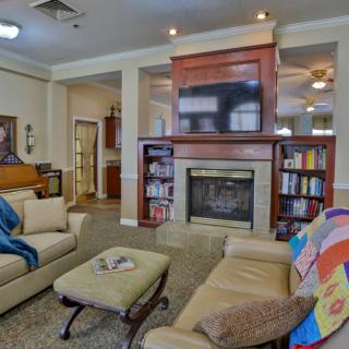 A cozy living room featuring a fireplace, bookshelves, and comfortable seating.