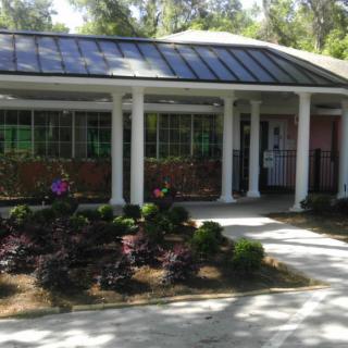 A residential house with a landscaped garden and covered porch supported by columns.
