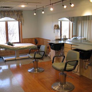 A serene and well-lit interior of a hair salon featuring styling chairs and a treatment table.