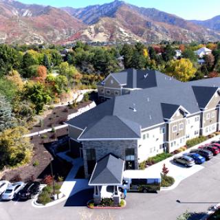 Aerial view of a modern building surrounded by vibrant autumn foliage and mountains.