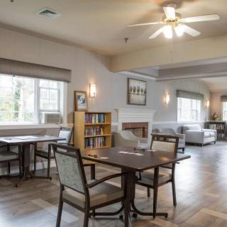 A cozy living and dining area featuring a ceiling fan, bookshelves, and ample seating.