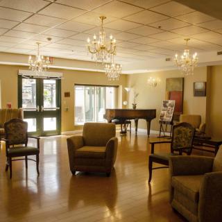 A cozy lounge area with comfortable seating and a grand piano, illuminated by elegant chandeliers.
