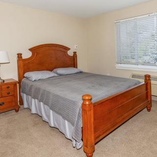 A cozy bedroom with a wooden bed frame, nightstand, and gray bedding.