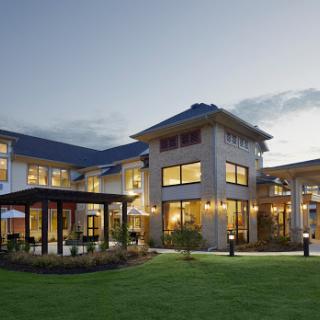 A modern residential building illuminated at dusk, showcasing stylish architecture and landscaped surroundings.