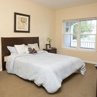 A cozy, well-lit bedroom featuring a neatly made bed with a large window allowing natural light.