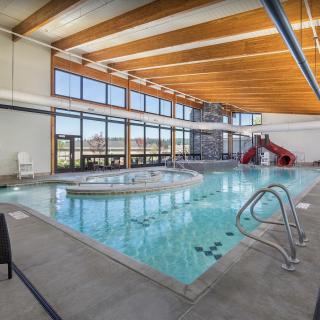 An indoor swimming pool with a water slide and ample natural lighting.