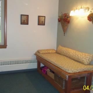 A cozy room with a daybed, wall decorations, and a window.