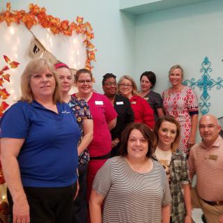 A group of people posing indoors with autumn-themed decorations.