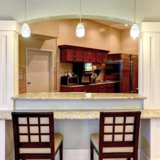A modern kitchen with bar seating and pendant lighting.