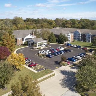 Aerial view of a residential building with a parking lot surrounded by trees.