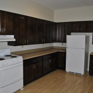A kitchen with dark wood cabinets, a white stove, and a refrigerator.