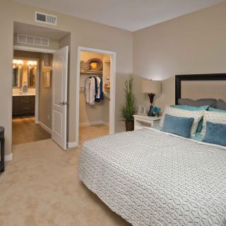 A modern bedroom with a neatly made bed, contemporary decor, and an adjacent bathroom.