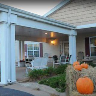 A cozy porch decorated with pumpkins for autumn, featuring outdoor seating.