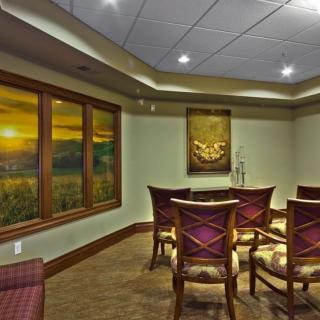 A well-decorated conference room with chairs arranged around a table, featuring a scenic window view and artwork on the wall.
