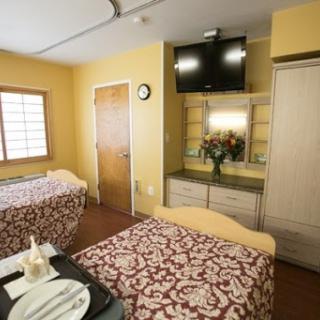 A cozy room with two beds, decorated in warm colors and equipped with a television.