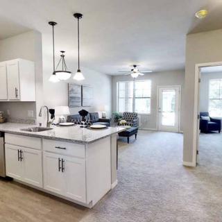 A modern open-concept apartment with a white cabinet kitchen and a spacious living area.