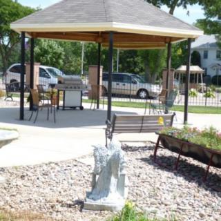 A tranquil park setting with a gazebo, benches, and a garden area.