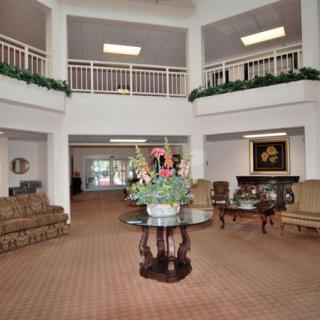 A spacious lobby area with sofas, a central table adorned with flowers, and a balcony overlooking the space.