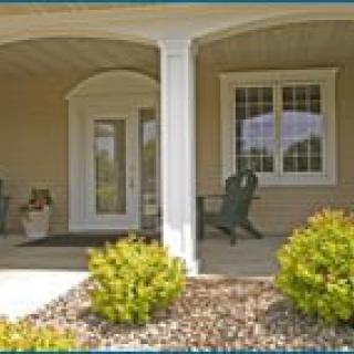 A welcoming front porch with a door, windows, and landscaping.