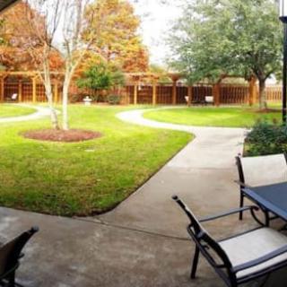 A peaceful backyard garden with a patio, surrounded by trees and a well-maintained lawn.