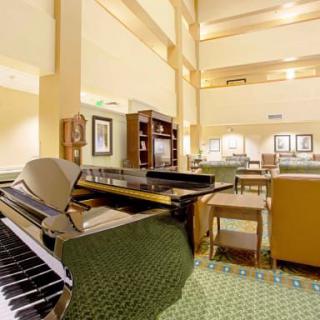 A spacious hotel lobby featuring a grand piano and elegant furnishings.