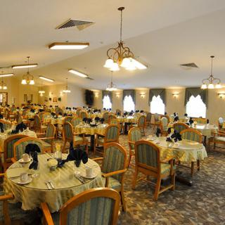 Elegantly set dining room with multiple tables and chairs, illuminated by warm lighting.