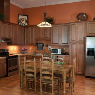 A spacious kitchen with wooden cabinets, a dining table, and stainless steel appliances.