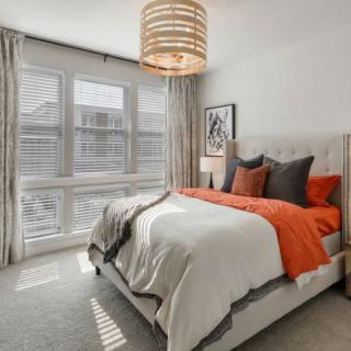 A modern bedroom with orange accent pillows and a cozy bed.