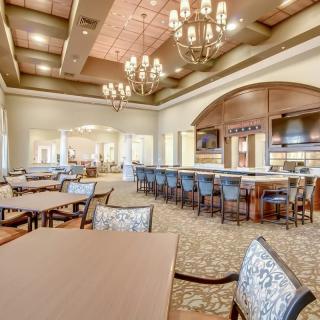 An upscale restaurant interior featuring elegant chandeliers and a spacious bar area.