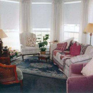 A cozy living room with a sofa, chairs, and lamps, featuring soft lighting and a touch of greenery.